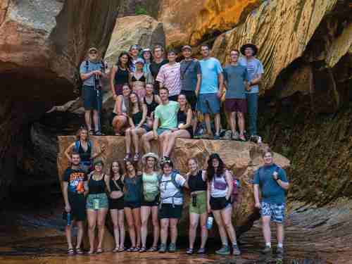 The entire group of students stands half on flat ground, half on a high rock so that we can see everyone